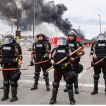State Police stand guard as smoke billows from buildings that continue to burn in the aftermath of a night of protests and violence following the death of George Floyd, in Minneapolis, Minn., on May 29, 2020. (Charlotte Cuthbertson/The Epoch Times)