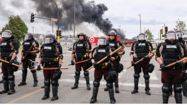 State Police stand guard as smoke billows from buildings that continue to burn in the aftermath of a night of protests and violence following the death of George Floyd, in Minneapolis, Minn., on May 29, 2020. (Charlotte Cuthbertson/The Epoch Times)