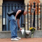 A man places flowers near the entrance to the park where three people were killed - REUTERS