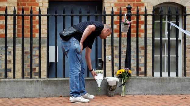 A man places flowers near the entrance to the park where three people were killed - REUTERS